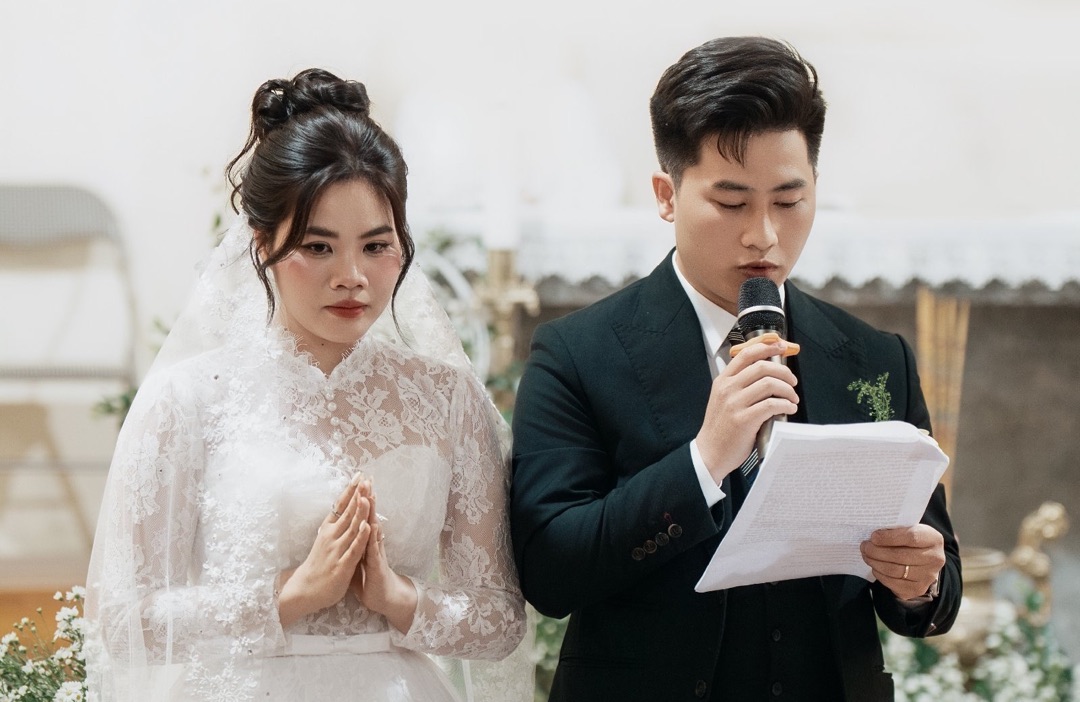 Chú rể cầm micro đọc lời cảm ơn cuối lễ cưới, cô dâu chắp tay đứng bên cạnh
